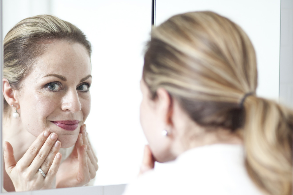 Lady looking in mirror - Green Beauty Expert