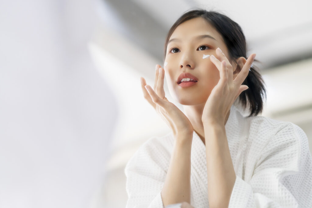 Young Asian woman applying moisturizer